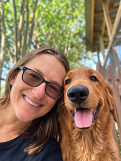 Lynette smiling with a golden retriever at the resort